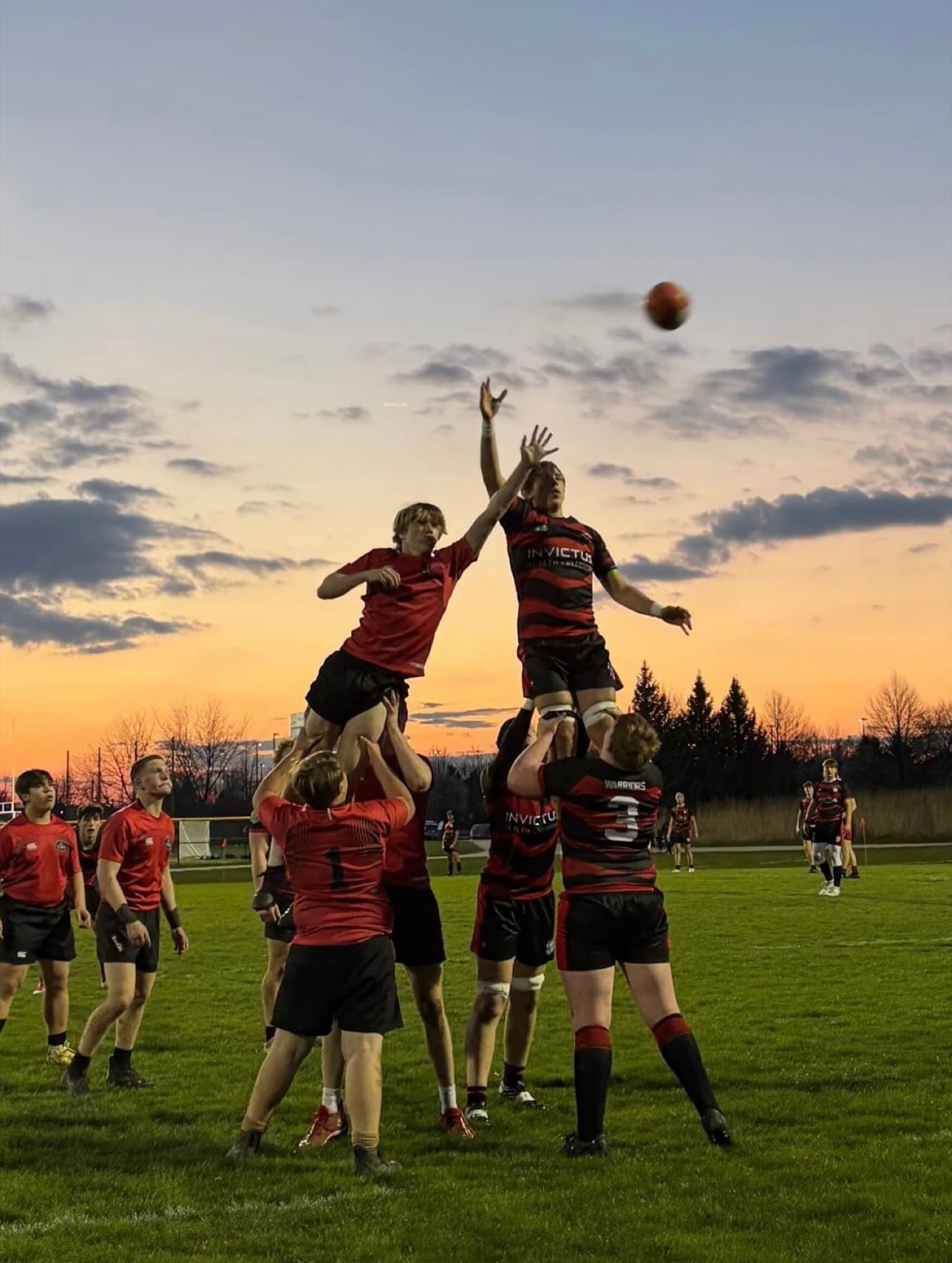 Fortivus players jumping for a ball at sunset